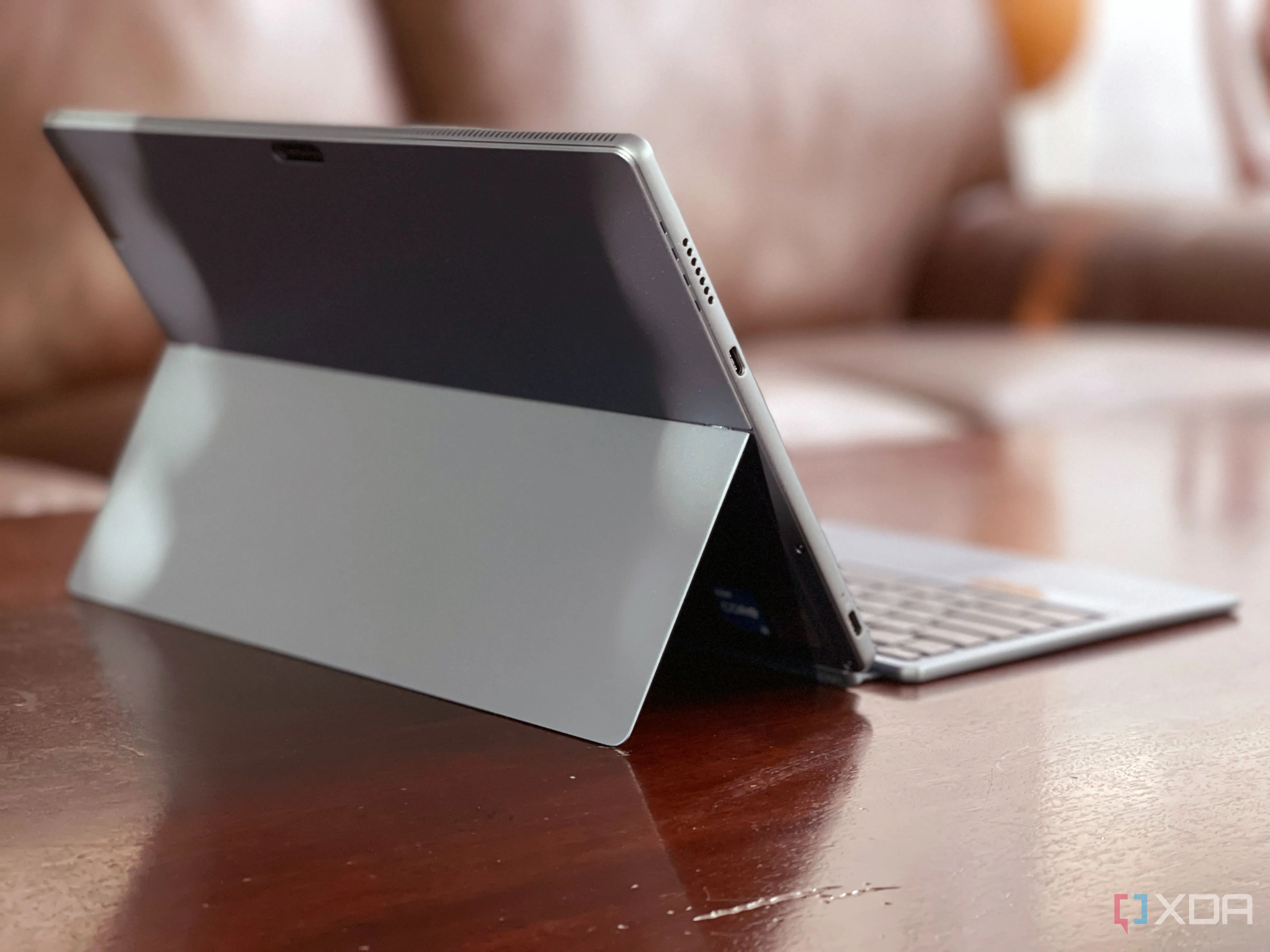 IdeaPad Duet 5i màu xám đặt trên bàn với ghế sofa phía sau