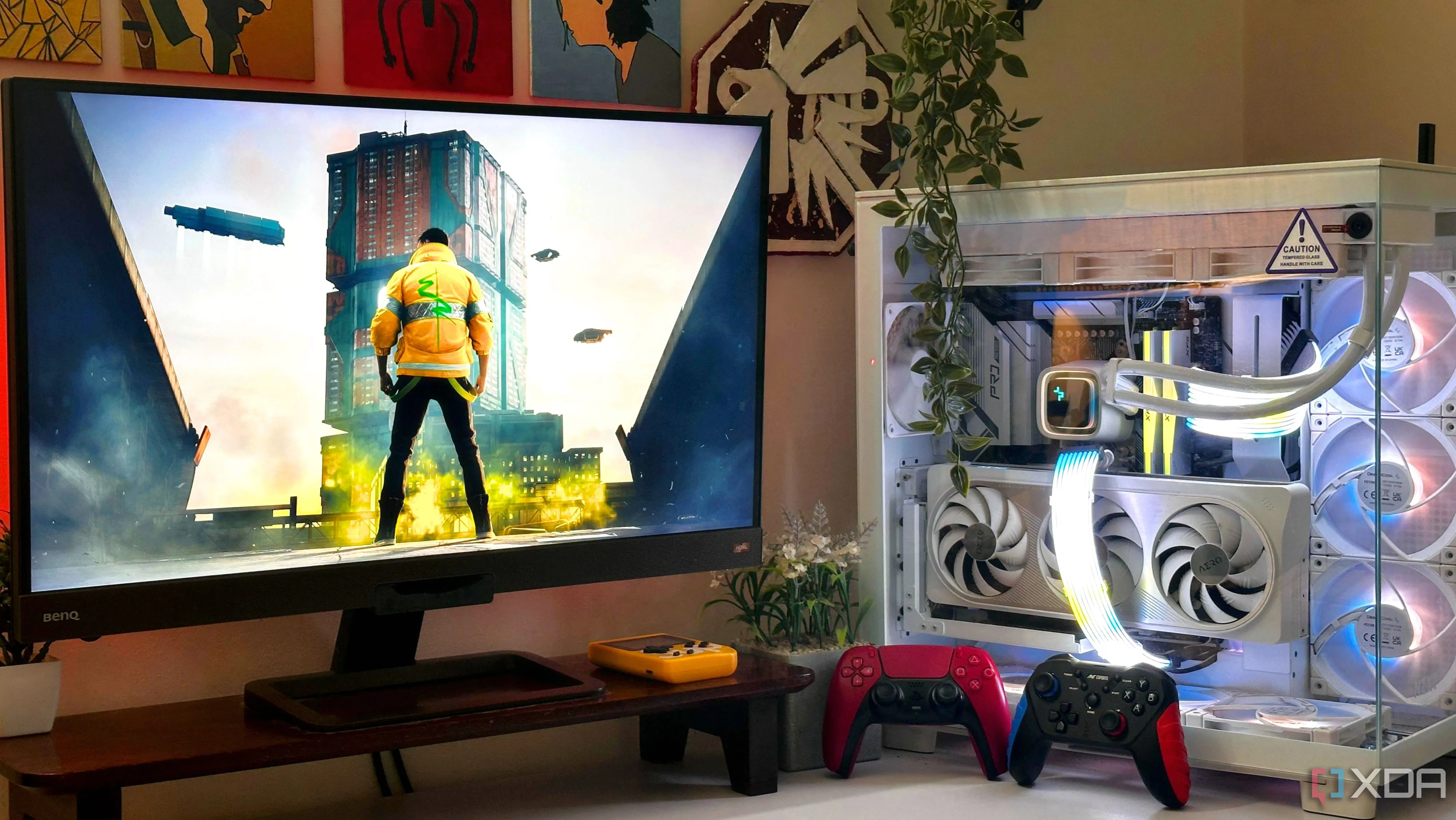 Một bộ PC chơi game với Cyberpunk 2077 trên màn hình, và hai tay cầm game đặt cạnh case PC.