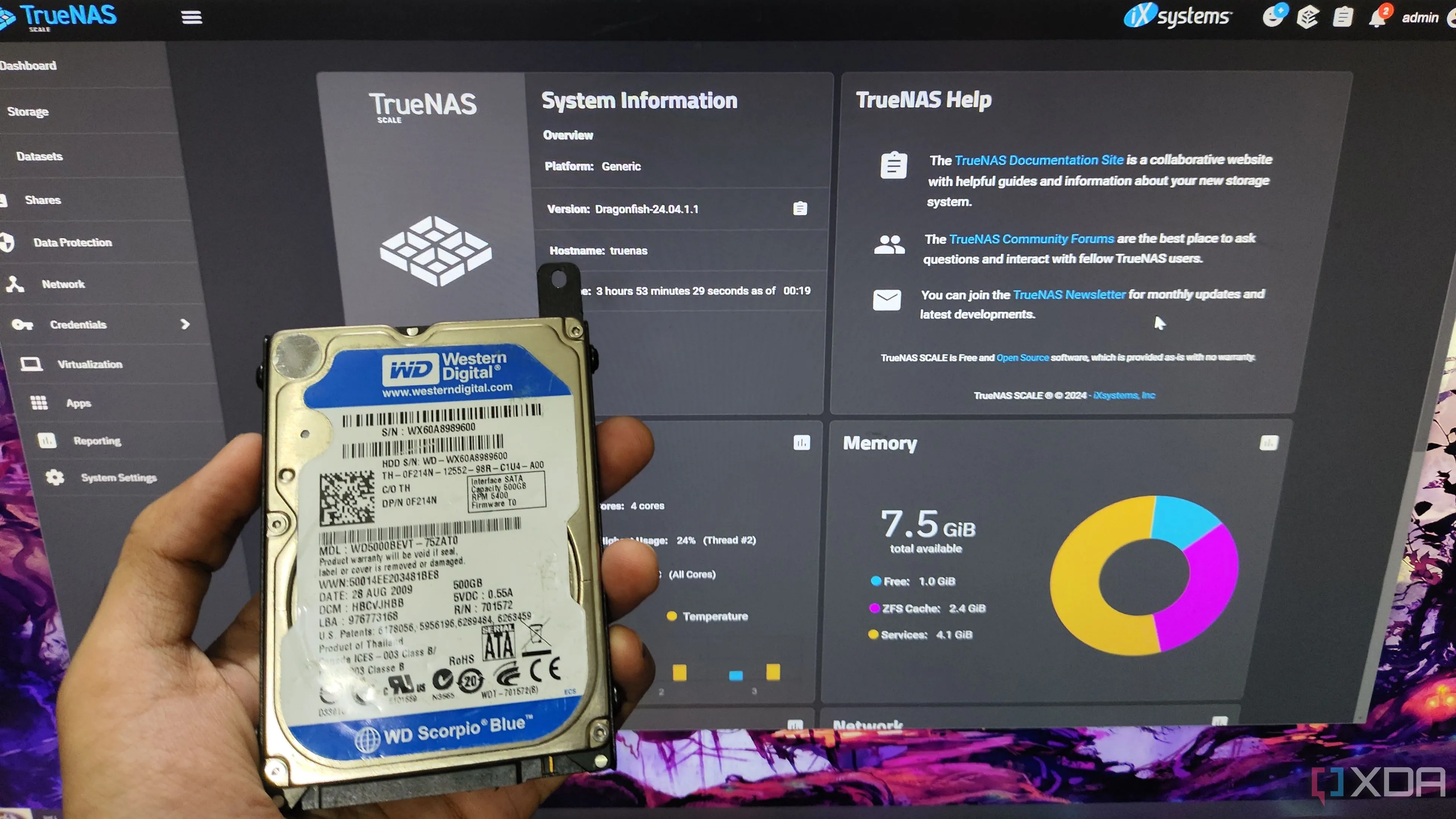 Một người cầm ổ cứng HDD trước màn hình hiển thị giao diện web TrueNAS Scale, minh họa việc sử dụng HDD trong hệ thống NAS.