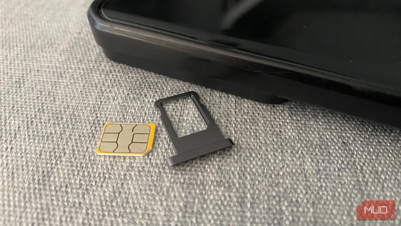 Thẻ SIM vật lý và khay đựng đặt cạnh điện thoại di động, minh họa việc sử dụng SIM truyền thống.
