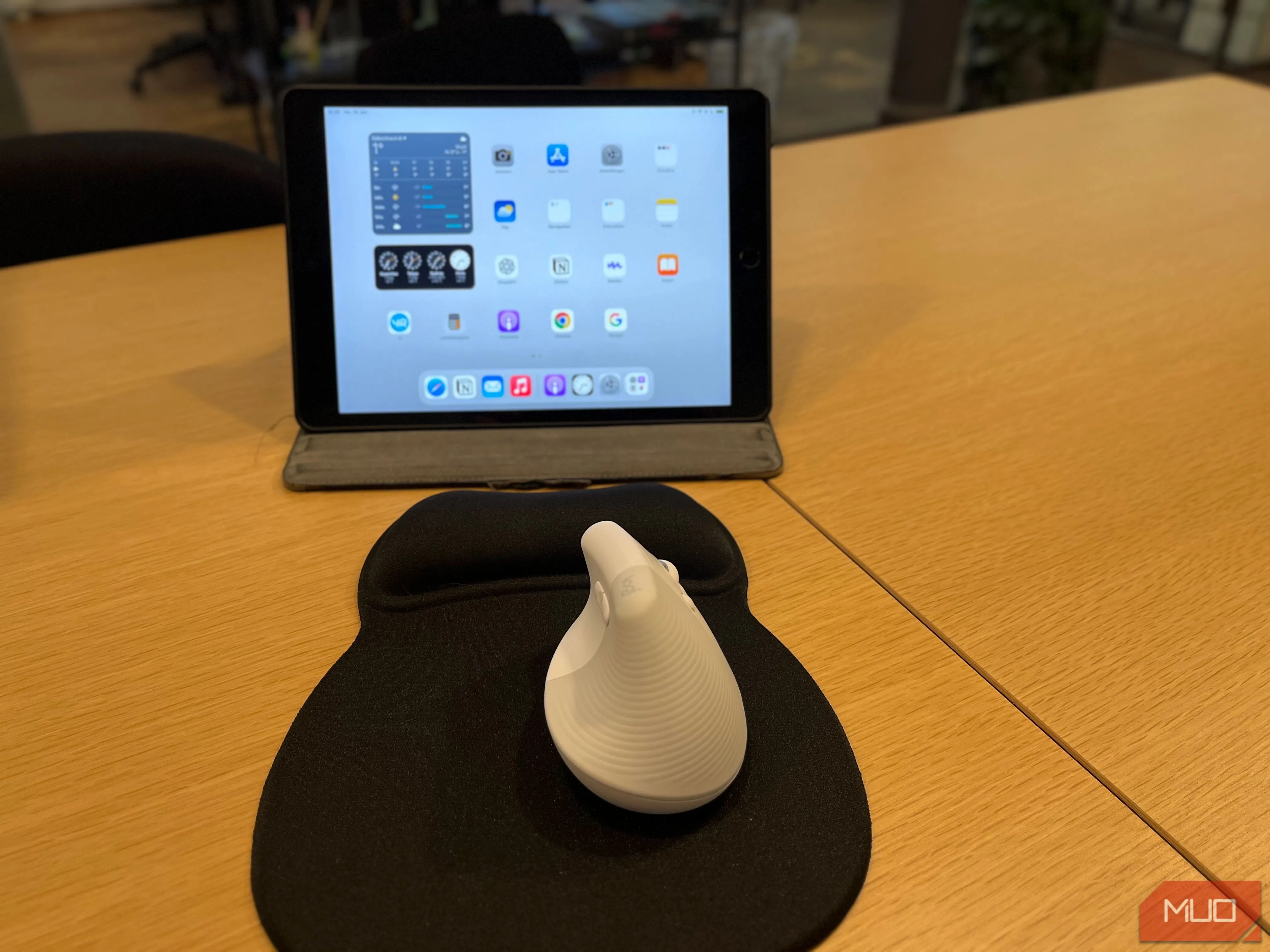 Bàn làm việc với iPad đang bật và chuột không dây màu trắng, minh họa khả năng kết nối đa thiết bị
