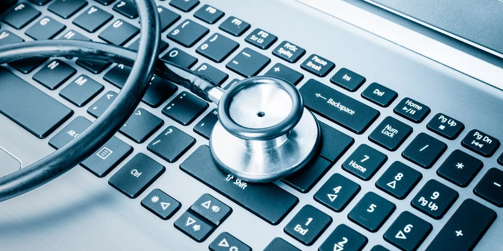 Bàn phím laptop và ống nghe y tế, tượng trưng cho việc hỗ trợ kỹ thuật và khắc phục sự cố công nghệ