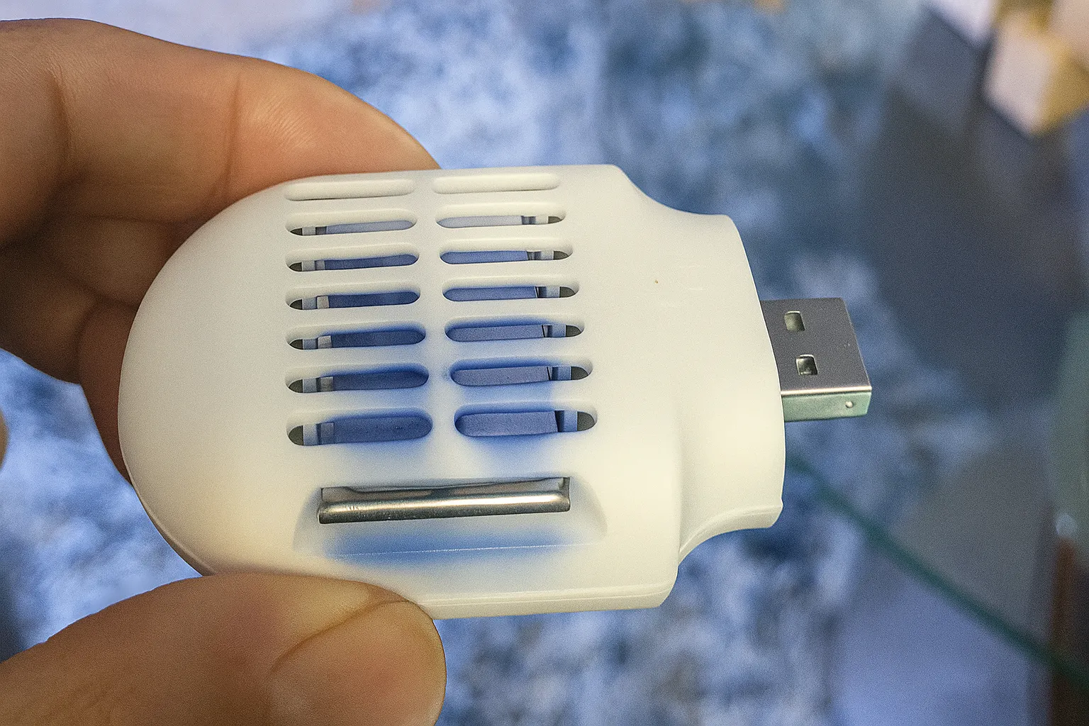 Bàn tay đang cầm thiết bị đuổi muỗi USB nhỏ gọn màu trắng