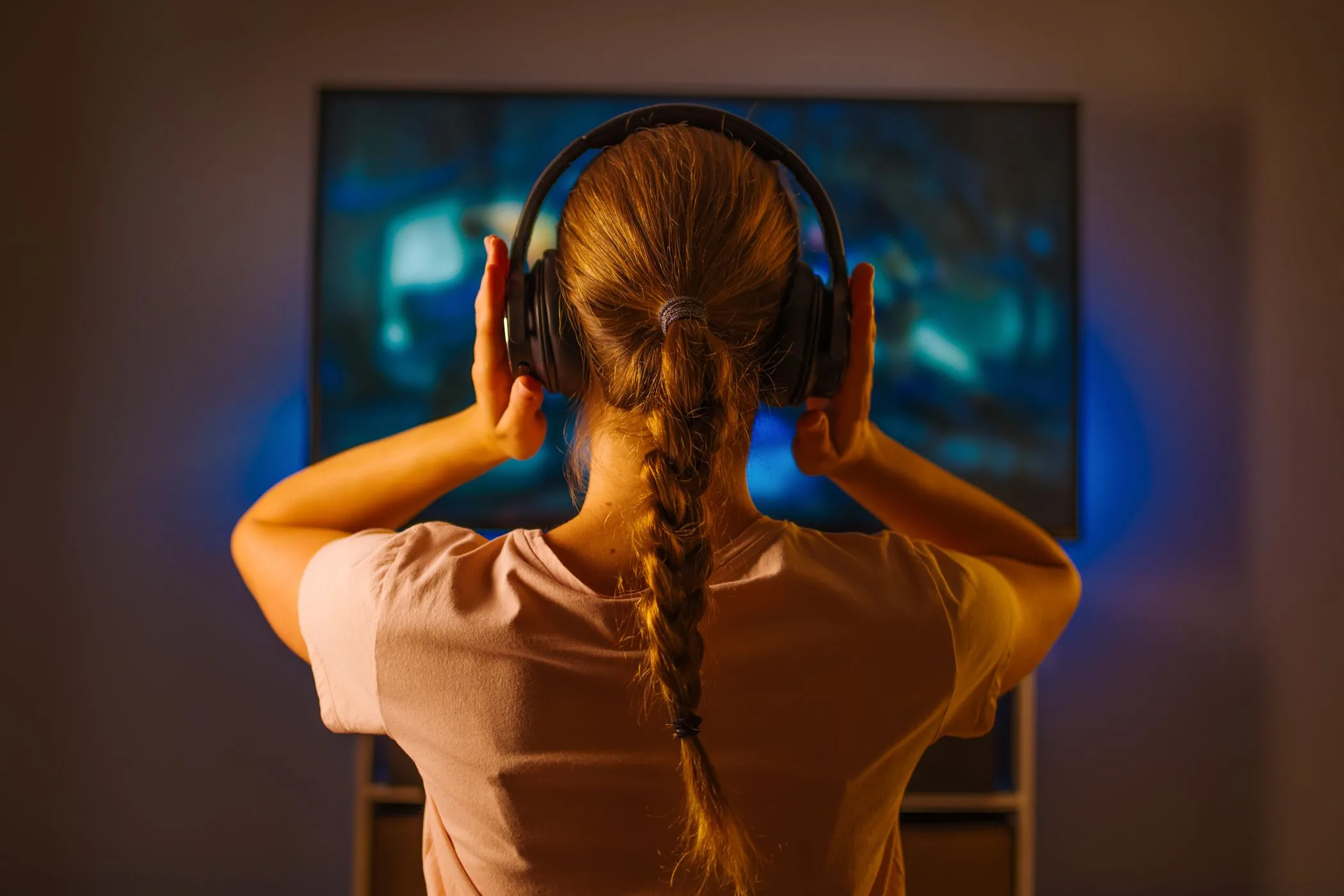 Cô gái trẻ đeo tai nghe, tập trung xem TV không phụ đề để cải thiện kỹ năng nghe.