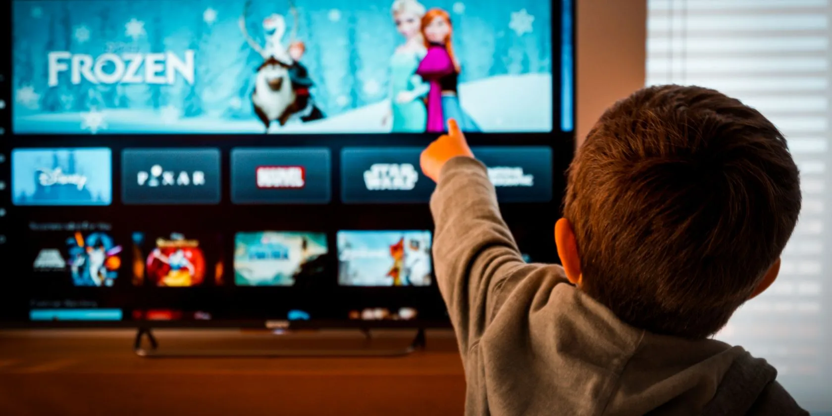 Hình ảnh một đứa trẻ đang chỉ vào biểu tượng Disney+ trên màn hình TV, thể hiện smart TV cũ được tận dụng làm trạm giải trí riêng cho trẻ em