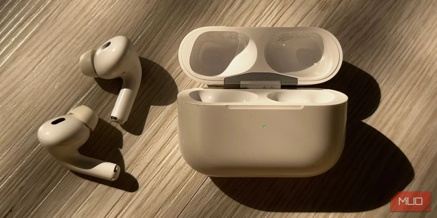 Hộp sạc AirPods với đèn trạng thái màu xanh lá cây, thể hiện thiết kế dạng hình chữ nhật nằm ngang của các dòng AirPods thế hệ 3 hoặc AirPods Pro