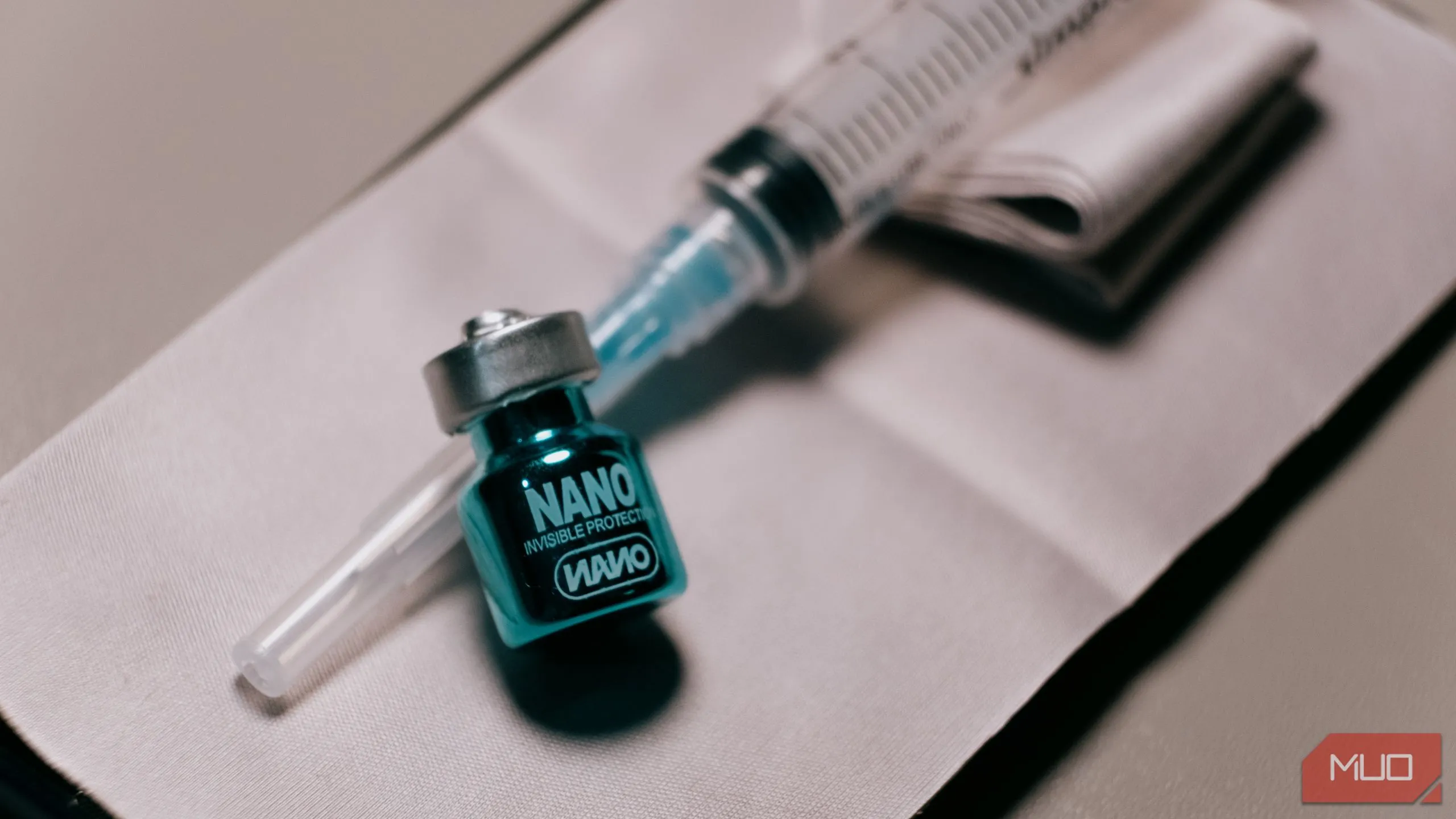 Lọ dung dịch phủ nano oleophobic nhỏ và ống tiêm, minh họa công nghệ phủ bảo vệ màn hình điện thoại.