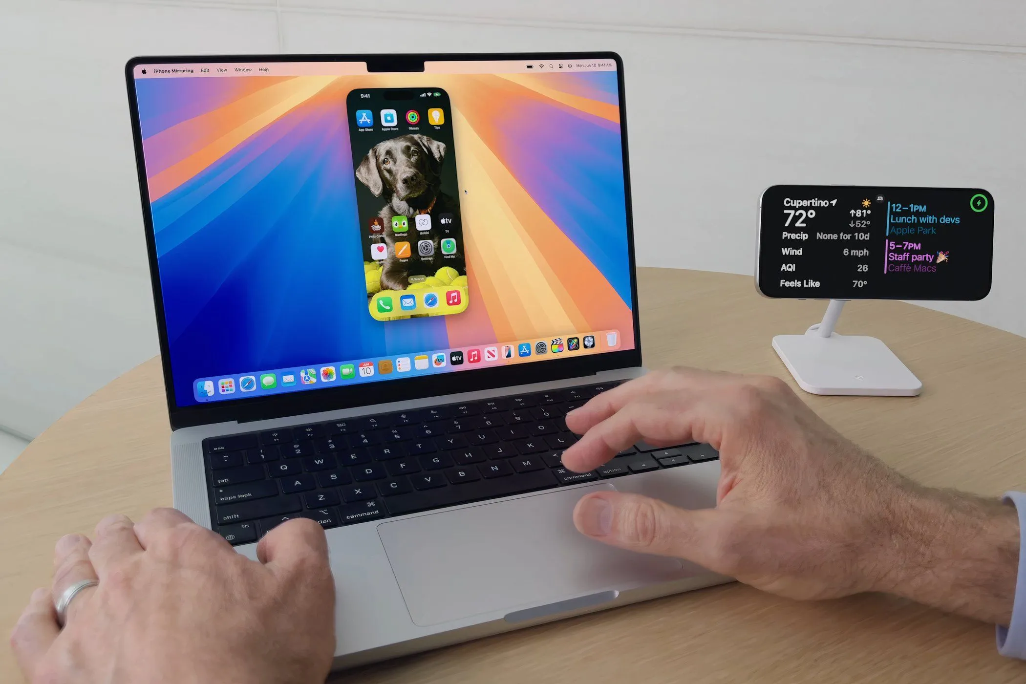 Một người đàn ông đang sử dụng MacBook Pro chạy macOS Sequoia với tính năng iPhone Mirroring