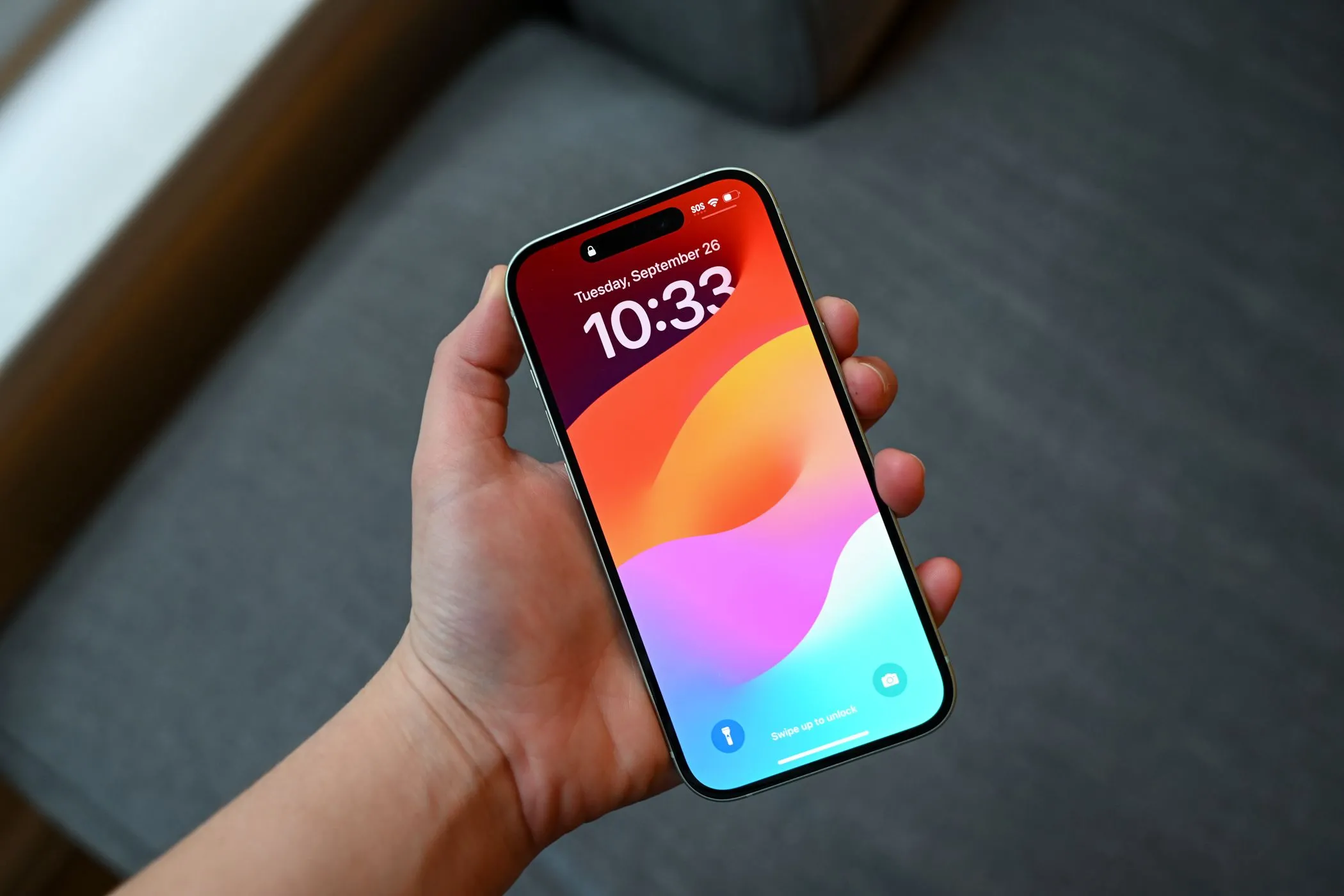 Người cầm điện thoại iPhone 15 đang hiển thị màn hình khóa