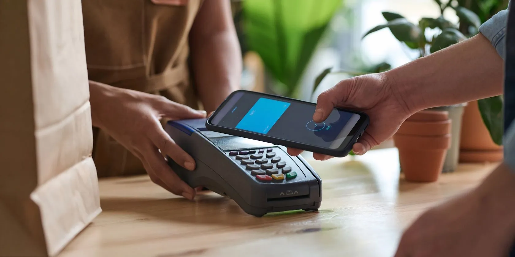 Người đàn ông thanh toán không tiếp xúc bằng điện thoại qua chip NFC tại cửa hàng tạp hóa