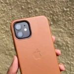 Người dùng cầm ốp lưng iPhone 12 da màu nâu vàng trên tay, minh họa vẻ đẹp và cảm giác cao cấp của ốp da Apple