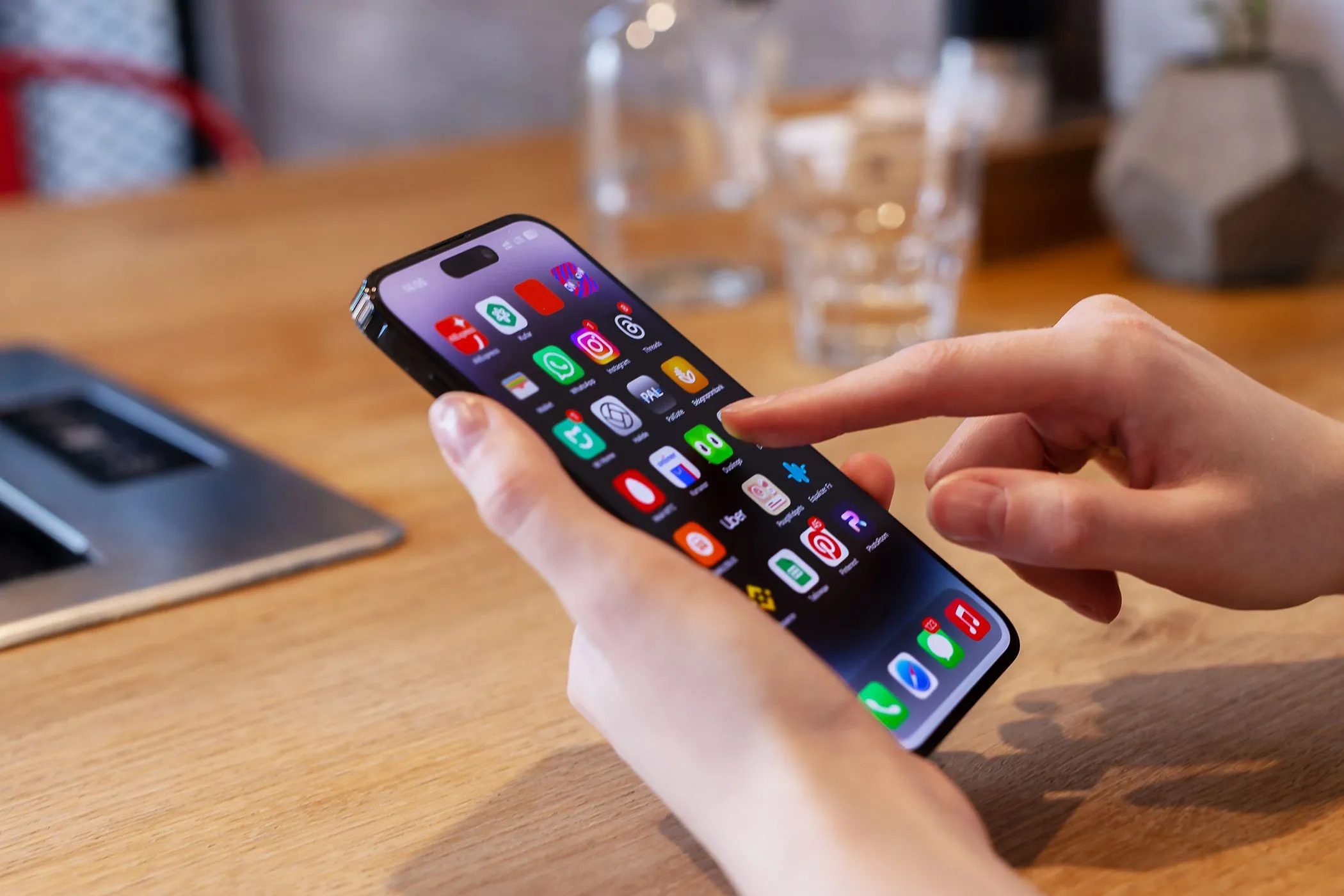Người dùng đang thao tác trên điện thoại iPhone tại bàn, minh họa việc thiếu tính năng liên kết nguồn khi chụp màn hình