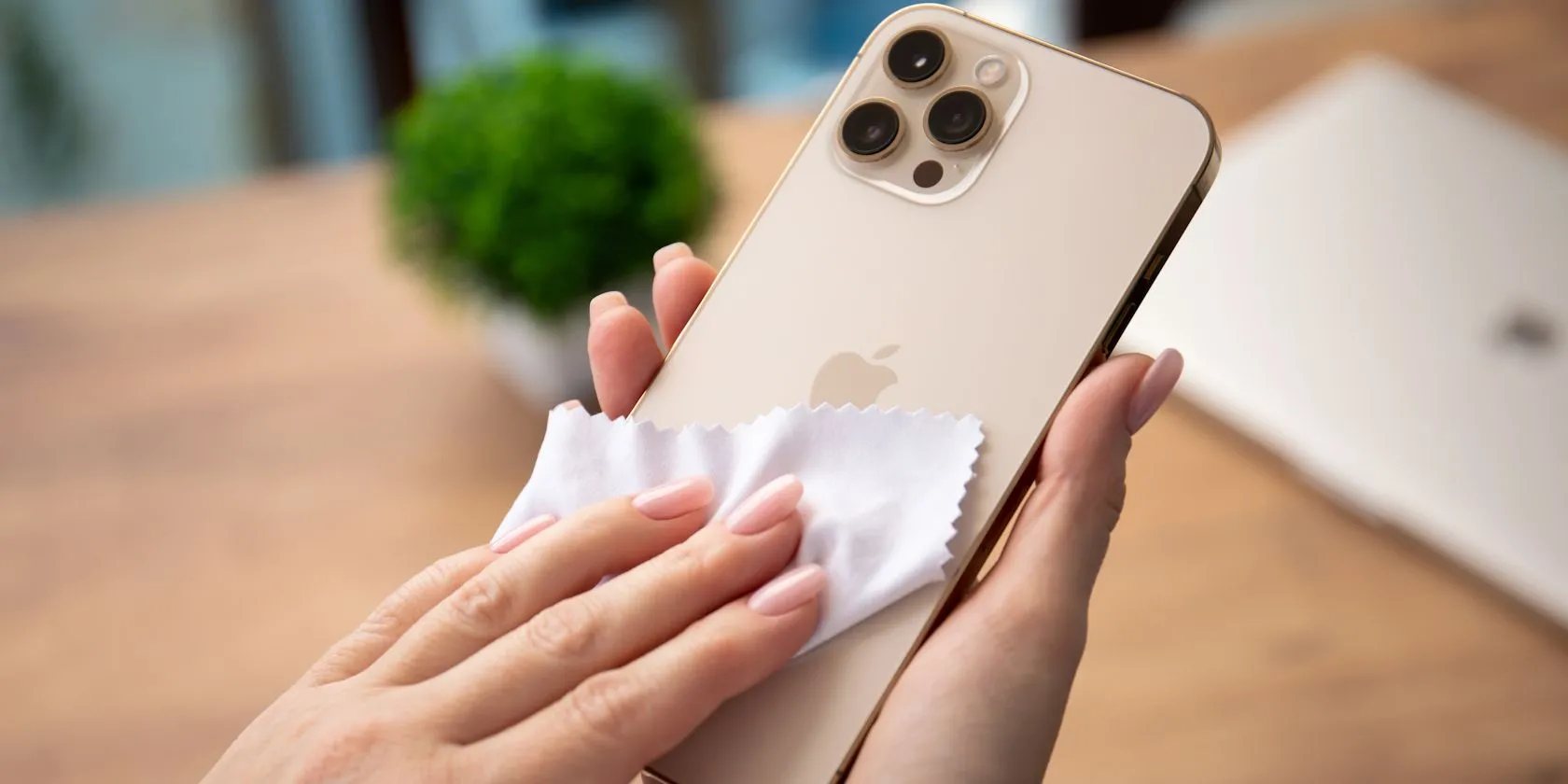 Người phụ nữ đang nhẹ nhàng lau sạch màn hình iPhone bằng vải sợi nhỏ chuyên dụng