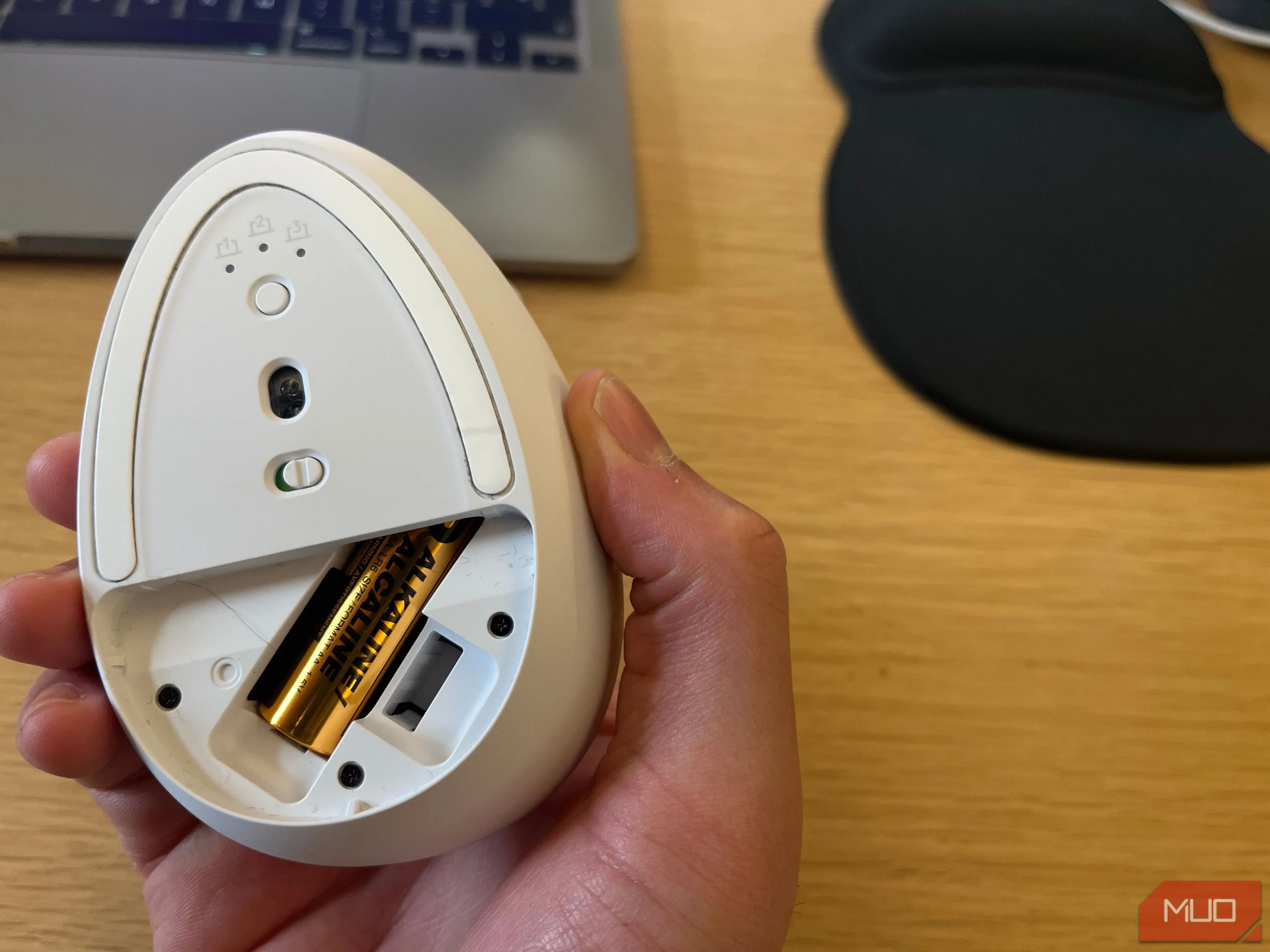 Pin tiểu AA đang được lắp vào khoang chứa pin của một chiếc chuột không dây Logitech, minh họa vấn đề pin thay thế